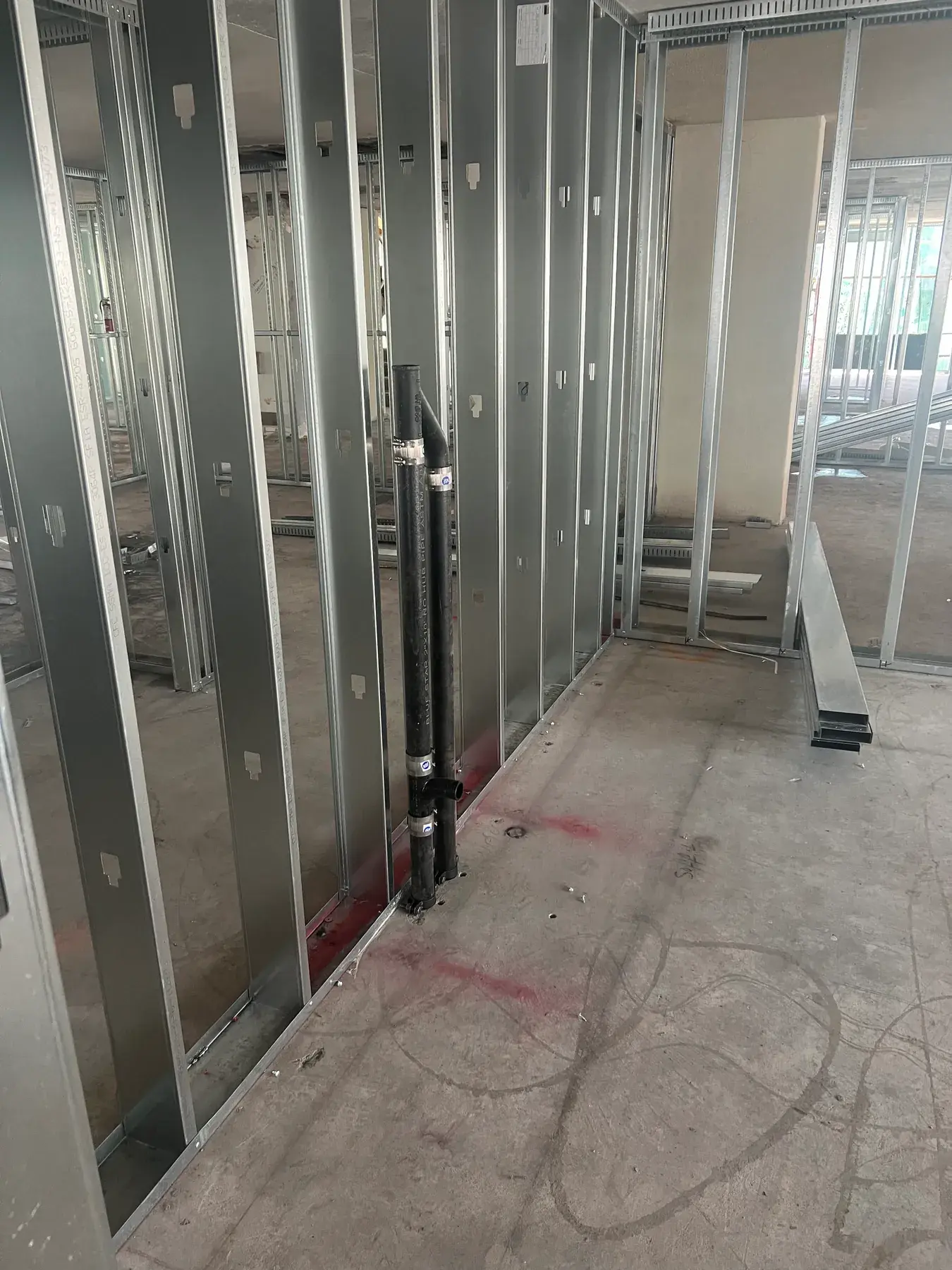 Interior metal stud partitions framed out with plumbing rough-in and floor layout markings