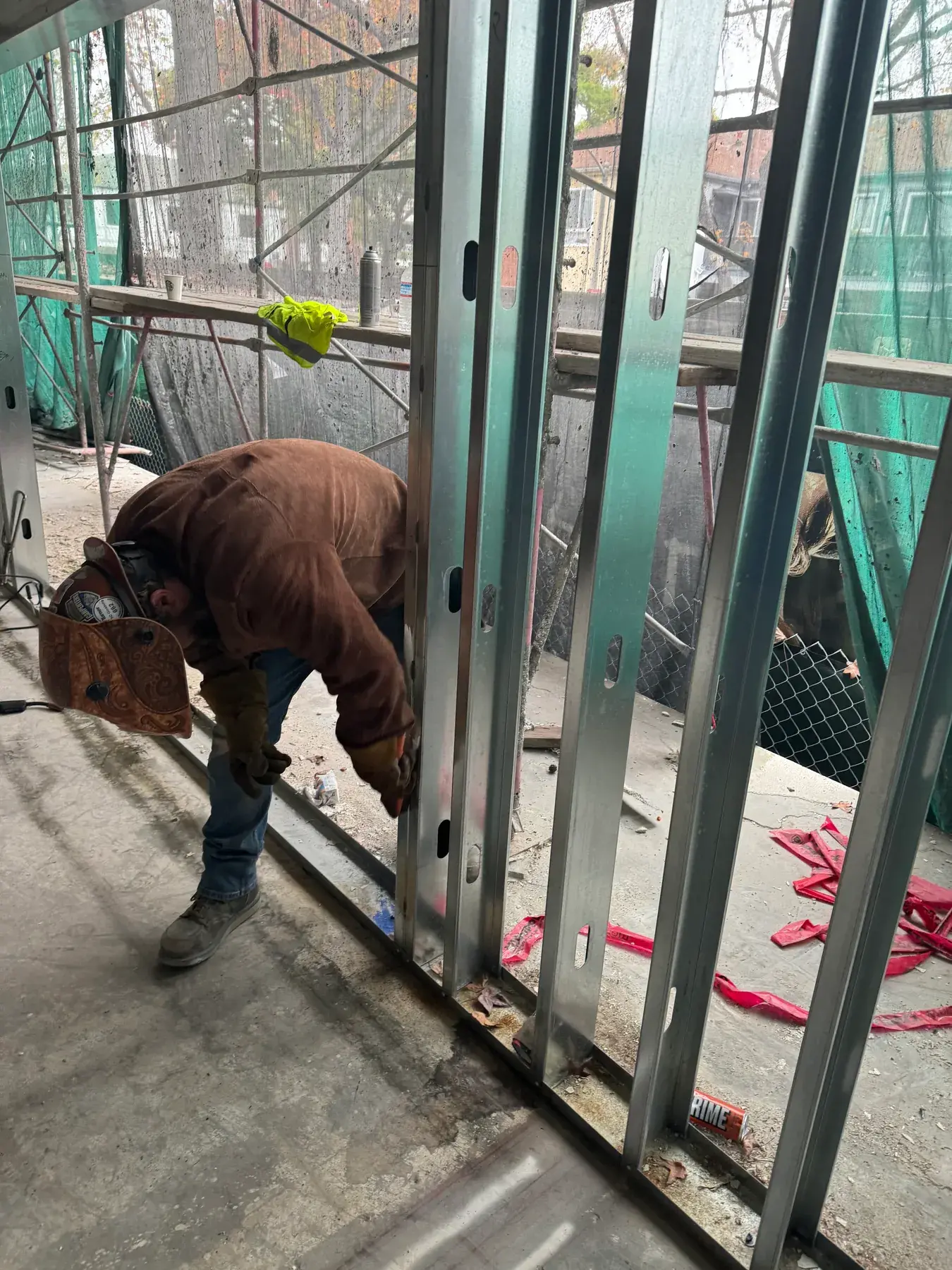 Framer fastening steel studs to the track at a building exterior wall