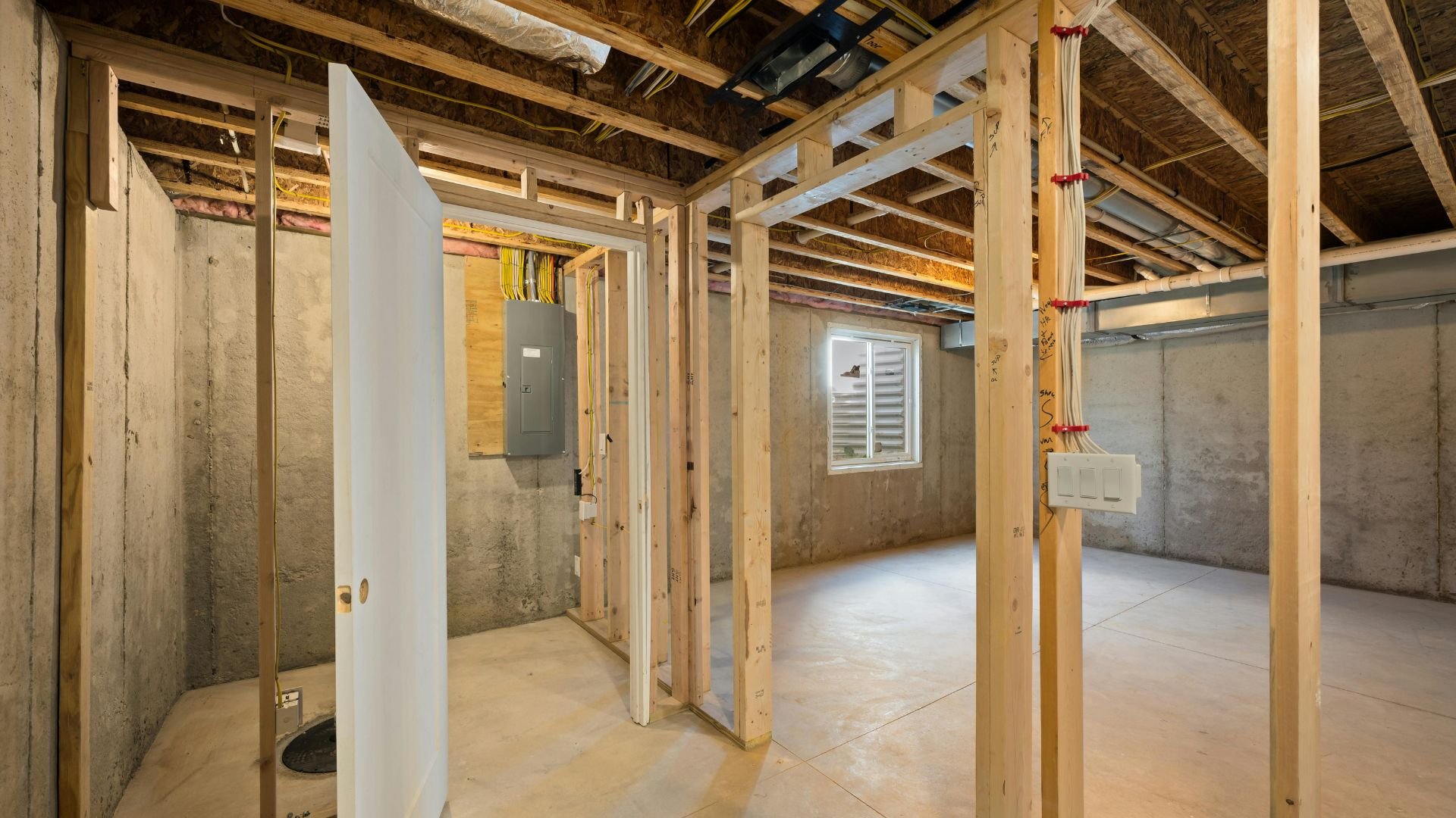 Unfinished basement interior with wood framing and concrete walls