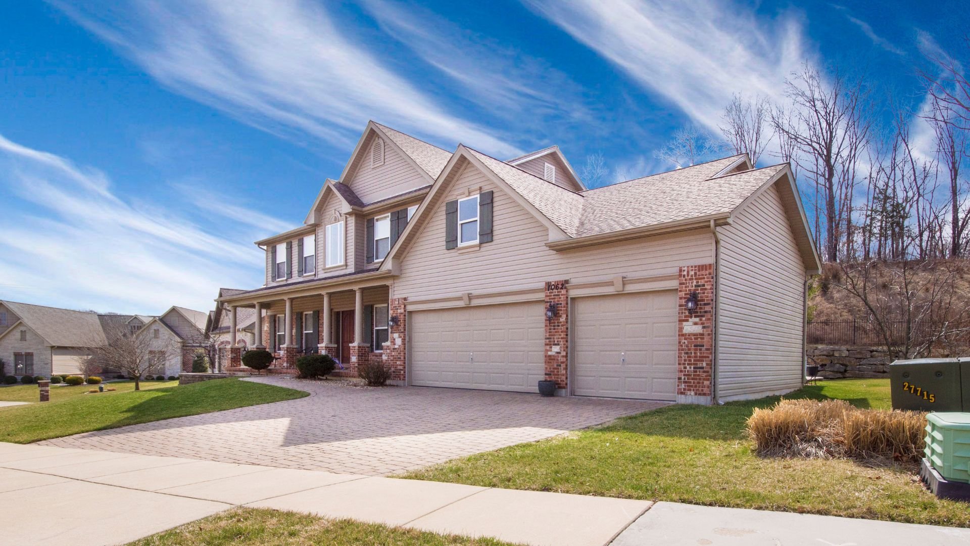 Two-story suburban house with brick accents and large garage on sunny day
